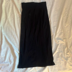 Svart långkjol med slits - En svart långkjol med hög midja och slits på sidan. Kjolen har en enkel och stilren design som gör den lätt att matcha. 