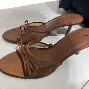 Bruna sandaler med rosett från Zara - Snygga bruna sandaler från Zara med öppen tå, låg klack och tunn meshdetalj. Storlek 40, använda en gång så fortfarande som nya