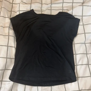 Svart träningstopp - Enkel svart topp köpt från stadium med märket energetics med rund halsringning och korta ärmar. Tillverkad i mjukt och lätt material som passar perfekt till träning eller sport. Snygg och stilren design utan mönster eller detaljer. Tröjan är i stl 122/128 men passar modellen utmärkt som vanligtvis har 146/152.