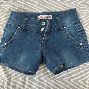 Vintage shorts  - As snygga mörkblåa och lågmidjade jeansshorts. Oanvända då de e fel storlek. 2 knappar framme och fina detaljer där bak. Storlek Xs kanske S.