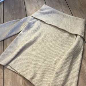 Beige ribbad stickad off shoulder tröja H&M - Supermysig beige stickad off shoulder tröja från H&M i ribbat material. Tröjan är ganska lång i modellen. Enkel att matcha med jeans eller kjol för en clean look. Använd ca 1 gång och är i fint skick