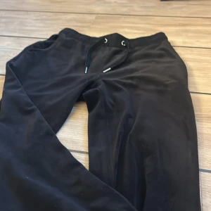 Svarta mjukisbyxor från Lindex stl 170 - Svarta mjukisbyxor från Lindex med dragsko i midjan och två bakfickor. Byxorna är i mjukt material och har en avslappnad passform, perfekta för chill dagar. Klassisk look med elastisk midja. Inte mycket använda så dom har ett bra skick