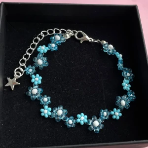 Handgjort- Blått pärlarmband med blommor och stjärnberlock - Supergulligt armband med små blommor av blå och vita pärlor, silverfärgad kedja och en söt stjärnberlock. Perfekt för dig som vill ha en lekfull och färgglad detalj till din stil.