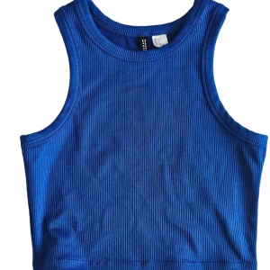 Blå ribbad linnetopp från HM - [KNAPPT ANVÄND] Snygg blå croppad linnetopp från H&M med ribbad struktur. Toppen är ärmlös och har en tight passform med rund halsringning. Perfekt att matcha med höga jeans eller kjol för en cool look.