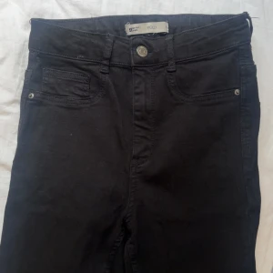 Svarta Molly jeans från Gina Tricot - Svarta Molly jeans från Gina Tricot med klassisk femficksdesign och knappstängning. 