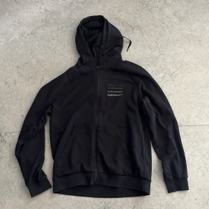Svart hoodie Peak Performance L - Svart hoodie från Peak Performance i storlek L. Tröjan har dragkedja, huva med snörning och fickor. Perfekt för chill dagar eller när du vill ha en clean streetstyle.