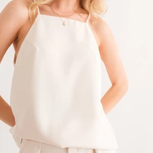 Vit linnetopp med tunna axelband - Stilren vit linnetopp med raka linjer och tunna axelband. Toppen har en lös passform och är tillverkad i ett slätt material som ger en clean look. Perfekt för varma dagar eller att styla lager på lager.