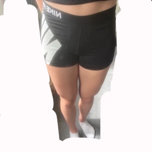 Nike Pro svarta tränings shorts - Svarta Nike Pro shorts med stor vit logga på sidan och bred resår i midjan. Tight passform och korta ben, perfekta för gym eller löpning. Tillverkade i stretchigt funktionsmaterial som andas bra. Det är storlek M, men jag har storlek S och de sitter jätte bra.