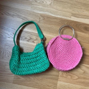 Två virkade väskor från H&M - Säljer två unika virkade väskor från H&M, i jätte bra skick . En grön axelväska med bred rem och en rund rosa handväska med metallhandtag. Båda är gjorda i stickad syntet och har riktigt somriga vibes. Perfekta accessoarer för att liva upp din outfit!
