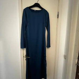 Mörkblå långklänning med lång ärm - En stilren mörkblå långklänning med rund halsringning och långa ärmar. Klänningen har en rak passform och är helt enfärgad utan detaljer eller mönster. Perfekt för dig som gillar minimalistisk och elegant stil. Storlek M men passar S också.
