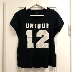 Svart t-shirt med tryck  - Svart T-shirt med vitt tryck med spruckna detaljer. Storlek XS men passar även S