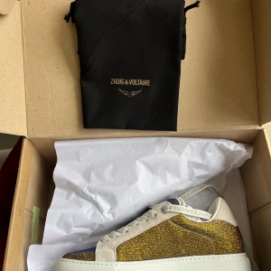 Glittriga sneakers från Zadig & Voltaire - Helt nya oprovade och oanvända sneakers från Zadig & Voltaire. Guld glittriga, beroende på ljus skiftar det mellan lite rosa/rött och blå/lila på det guldiga. Super snygga, coola och trendiga skor i storlek 37! 😍😍de är såklart äkta, qr finns där på kartongen, allt följer med vid köp! 
