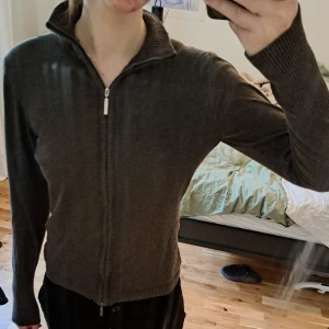 Mörkgrön kofta med dragkedja - Mörkgrön kofta med hel dragkedja framtill och hög ribbad krage. Långa ärmar med breda ribbade muddar. Om ni vill se fler bilder eller har en fråga är det bara att höra av sig <3