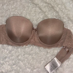 Beige axelbandslös bh med spetsdetaljer - Snygg beige axelbandslös bh med spetsdetaljer. Perfekt för klänningar och toppar utan axelband. Bekväm passform och stilren design. (Mammas från 90’s)❤️