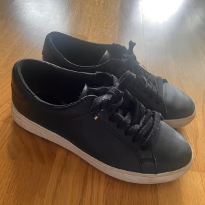 Svarta sneakers från Michael Kors - Snygga svarta sneakers från Michael Kors med klassisk design. Skorna har en vit sula och svarta snören.