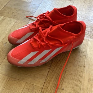 Adidas crazy fast  - Säljer ett par röda fotbollsskor från Adidas med vita detaljer och snörning. Skorna har dobbar för bra grepp på planen och en tight passform för optimal kontroll. Perfekta för fotbollsspelare som vill ha stil och funktionalitet. (Bara använda 10 gånger)