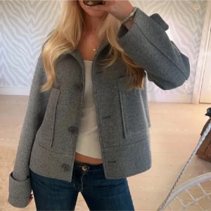 Grå kappa  - Snygg grå ulljacka från Kappahl med stora knappar och bred krage. Säljer då den tyvärr inte kommer till användning längre, strök xs nypris 800