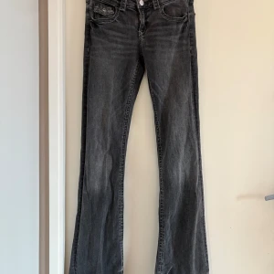 Grå bootcut jeans från Gina Tricot - Snygga grå bootcut jeans från Gina Tricot. De har en klassisk femficksdesign och knappar framtill. I modellen tall så det passar mig som vanligtvis har xs. Mått: midja: 68, innerben: 81 cm