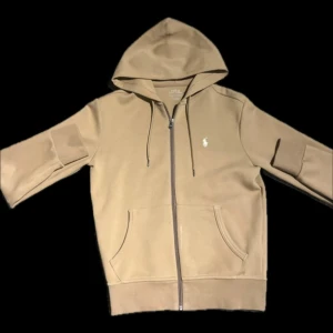 Beige hoodie från Ralph Lauren - En beige Ralph Lauren zip i storlek XS. I ett nyskick. Utan defekter. Från märket Polo Ralph Lauren. Köpt för 2295kr.