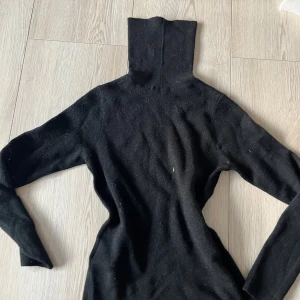 Svart polotröja från American Vintage - Säljer en stilren svart polotröja från American Vintage. Tröjan är stickad och har långa ärmar, perfekt för kyligare dagar. Den har en klassisk design med ribbade detaljer vid ärmslut och nederkant.🩷🩷