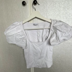 Vit ribbad topp från Zara💓 - Säljer en söt vit ribbad topp från Zara med puffiga korta ärmar. Toppen har en rund halsringning och är perfekt för en stilren look. Passar bra till både jeans och kjol. 🌟