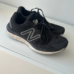 Svarta New Balance sneakers - Säljer ett par svarta New Balance sneakers med snörning och rund tå. Skorna har en slitstark sula och är perfekta för träning eller vardagsbruk. De har en klassisk design med det ikoniska N-logotypen på sidan.