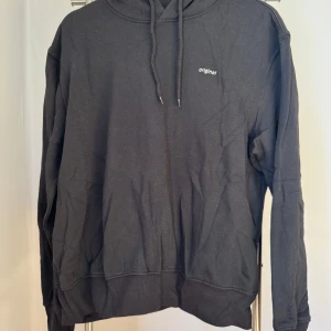 Ny, oanvänd, svart hoodie från H&M!  - Ny, oanvänd, svart hoodie med prislappen kvar i storlek M från H&M Divided. Hoodien har en vit text på bröstet som lyder ”original”. Nypris 149kr