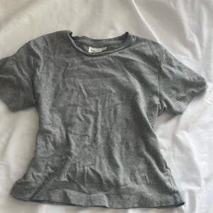 Grå t-shirt från Kappahl - Säljer en enkel och stilren grå t-shirt från Kappahl. Perfekt för en avslappnad look. T-shirten har korta ärmar och en rund halsringning.