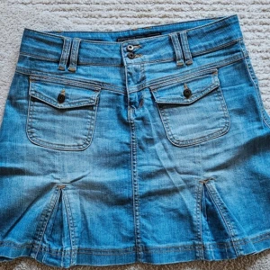 Jeanskjol med fickor - Snygg jeanskjol i blå denim med dubbla knappar . Köpt second hand men var tyvärr lite stor. Lånade bilder