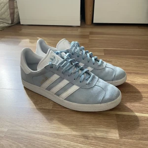 Ljusblå Adidas Gazelle sneakers - Säljer ett par stilrena ljusblå Adidas Gazelle. Skorna är i bra skick och använda fåtal gånger. Strl 43 1/3. Tveka inte att höra av dig vid eventuella funderingar :)