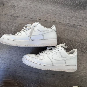 Vita Nike Air Force sneakers - Säljer ett par klassiska vita Nike Air Force sneakers. De har en rund tå och snörning framtill. Perfekta för en stilren look. Lite creased men fortfarande fina.