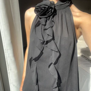 Snygg svart blus från Zara - Snygg svart blus från Zara med en elegant blomma vid halsen. Perfekt för festliga tillfällen💓Blusen har fortfarande prislappen på och är i strl xs men passar också s💗Säljer pågrund av att den inte kommer till användning💓