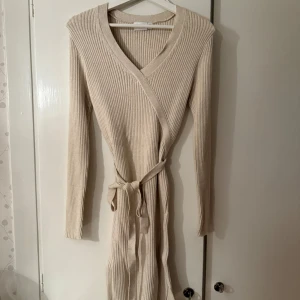 Beige ribbad omlottklänning från vila - Superfin beige omlottklänning från Vila i ribbat, stretchigt material som sitter som en dröm! V-ringad med knytband i midjan, långa ärmar och en liten slits nertill – en riktig garderobsfavorit. Märkt som storlek XS, men väldigt stretchig och passar även dig som vanligtvis bär storlek M (som jag!). Endast använd en gång, i toppskick. Passa på innan den försvinner! Pris kan självklart diskuteras 🌸💕