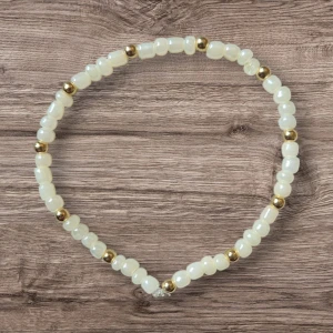 Pärlarmband med vita och guldpärlor - Elegant armband med vita pärlor och små guldfärgade pärlor emellan. Perfekt för att ge en stilren touch till din outfit. Armbandet är elastiskt och passar de flesta handleder.