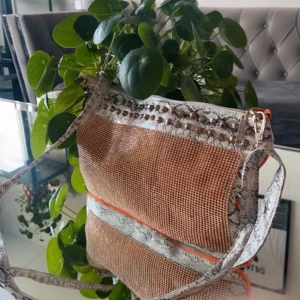 Glittrig axelväska med ormskinnsmönster - Snygg och trendig axelväska med glittrigt material och ormskinnsmönstrade detaljer. Väskan har en justerbar axelrem och en dragkedja upptill. Perfekt för att ge din outfit en extra touch av glamour.