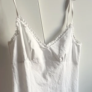 Vit klänning - Stilren vit klänning med smala axelband och v-ringad design. Så vacker nu till sommaren 