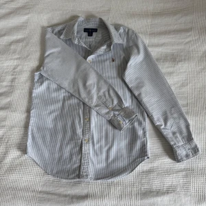 Randig skjorta från Ralph Lauren - Säljer en stilren randig skjorta från Ralph Lauren i blått och vitt som passar perfekt till sommaren. Skjortan har bra passform och knappar framtill samt en broderad logotyp på bröstet. Perfekt för en klassisk look. Passar som XS. 