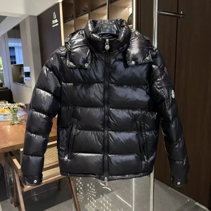 Moncler jacka  - Säljer en snygg svart dunjacka från Moncler. Jackan har en glansig finish och är utrustad med dragkedja och huva. Perfekt för kyliga dagar med sin pufferdesign som håller dig varm. Den har långa ärmar och praktiska fickor framtill. Samt till vindiga dagar i sommras där du kan även köpa in jäckan tills kylan kickar in