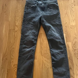 Grå jeansbyxor - Snygga grå jeansbyxor med en klassisk femficksdesign. De har en normal passform och är perfekta för en stilren look. Byxorna har en dragkedja och knapp framtill. J Lindberg, W29/L32