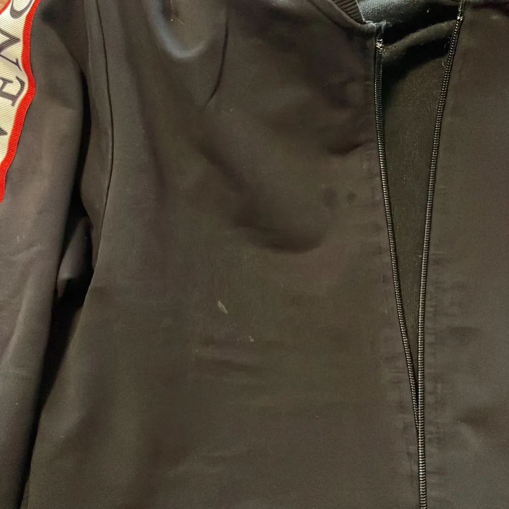 Säljer en stilren svart bomberjacka från Givenchy med dragkedja framtill. Jackan har långa ärmar med Givenchy-logga längs sidorna i vitt och rött. Perfekt för en trendig look! Lite småfleckar. Kolla bild. . Takit.