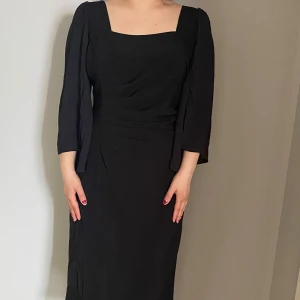 Svart klänning  - Elegant svart klänning med trekvartsärm och en smickrande passform. Klänningen har en stilren design med en diskret dragkedja i ryggen. Perfekt för en stilfull look.