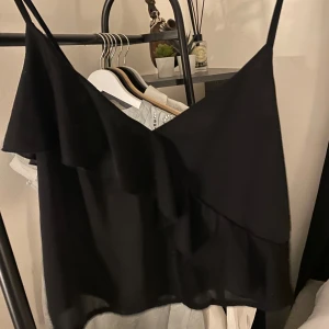 Svart topp med volang - Snygg topp från HM använd ett fåtal gånger- inga deffekter!