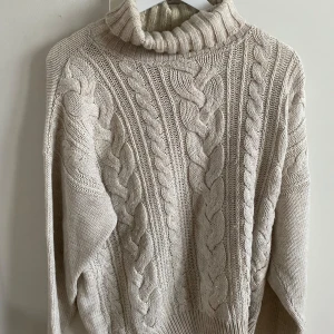 Beige stickad polotröja - Säljer en beige stickad polotröja med flätmönster. Tröjan har en hög polokrage och långa ärmar. Den har några defekter men ändå i relativt bra skick! Det står XL på lappen men jag skulle säga mer L/M
