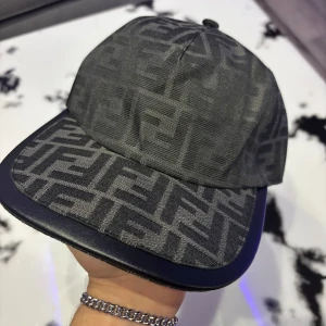 Fendi keps - Snygg grå keps från Fendi med ett stilrent mönster. Kepsen har en klassisk design med böjd skärm och justerbar passform. Perfekt för att ge din outfit en lyxig touch. M