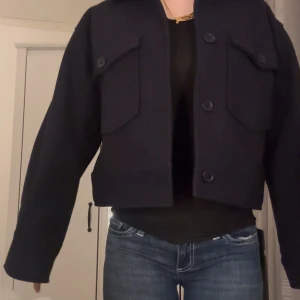 Kappa - Snygg marinblå kappa med stora knappar och två framfickor. Jackan har en croppad passform och långa ärmar, perfekt för en stilren look.