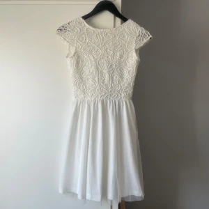 Vit studentklänning - Vit studentklänning "Ayla" från Bubbleroom i storlek 34. Stängs med dold dragkedja och knappar i ryggen. Endast provad, lapp kvar. Plaggets längd: cirka 83 cm. 200kr