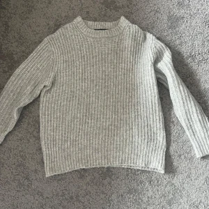 Grå stickad tröja XS - Säljer en mysig grå stickad tröja med långärmad design. Perfekt för kyliga dagar med sin ribbade struktur och bekväma passform. Ett måste i garderoben för en stilren look.Från lager 157 i storlek XS