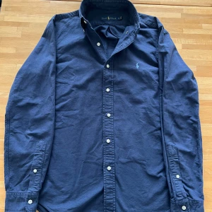 Ralph Lauren Skorta - Säljer riktigt sjysst Marinblå skjorta från Ralph Lauren🍾. Den är i storlek S och är riktigt skön att bära på, speciellt nu till våren och sommaren! Skickar alltid 24 timmar📦Nypris ca 1500kr, vårt pris 599kr✅Hör av vid mer bilder eller funderingar mvh D-H Clothing💯