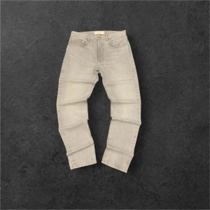 Grå jeans från Jeanerica - Snygga grå jeans från Jeanerica med klassisk femficksdesign och knappgylf. Perfekta för en stilren look. De har en rak passform och är tillverkade i ett slitstarkt denimtyg. Storlek 31/34