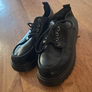 Svarta snörskor i skinn - Snygga svarta snörskor i skinn med rund tå och robust sula. Perfekta för en stilren look. Skorna har klassisk snörning och en diskret design som passar till många olika outfits.
